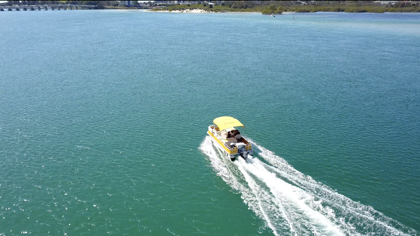 Yellow BBQ boat cruising across Wallis Lake at Boatshed Number One, Forster